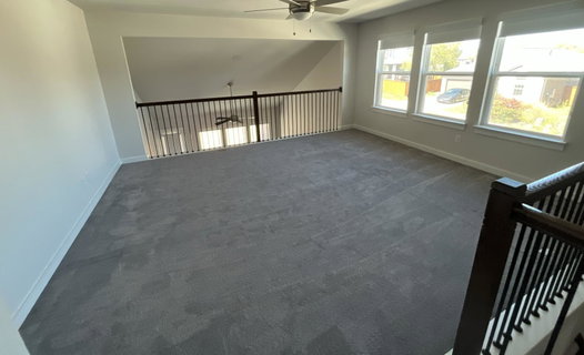 Empty room featuring dark carpet and a ceiling fan