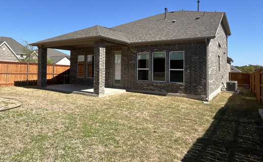 Back of house with brick siding, a fenced backyar