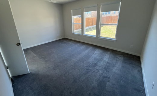 Empty room with dark colored carpet and baseboards